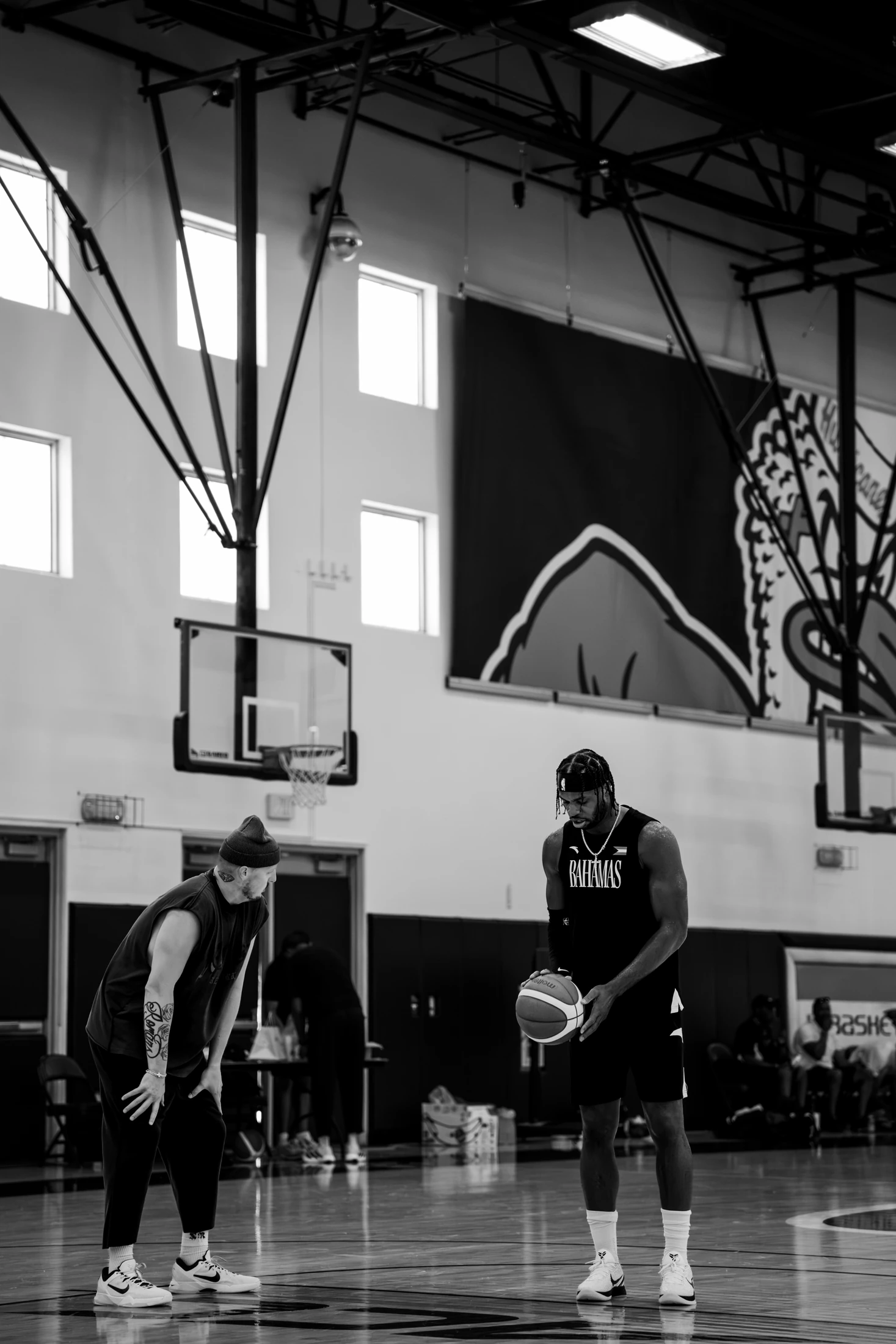 Trey Slate leans in to coach a player holding the ball during training.